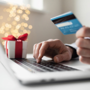 Person with credit card in their hand browsing for gifts on their laptop