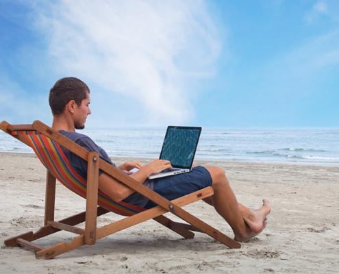 Man sitting on the beach with his laptop